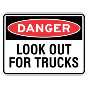 Imagine a shiny metal sign that has a special covering to protect it from the sun. On this sign, it says in big letters, "DANGER - Look Out For Trucks." It's there to keep you safe and remind you to be careful around big trucks.