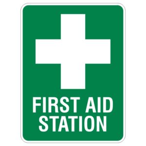A green sign displaying a white medical cross and the words FIRST AID STATION in bold letters.