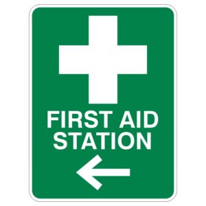 A green sign displaying a white cross symbol and the text FIRST AID STATION with a left-pointing arrow.