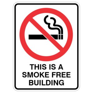 A sign featuring a red circle with a diagonal line over a black cigarette icon and smoke, accompanied by the text THIS IS A SMOKE FREE BUILDING below.