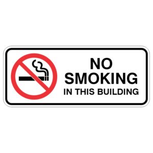 A rectangular sign with a red circle and diagonal line over a cigarette symbol, stating NO SMOKING IN THIS BUILDING in bold black letters.