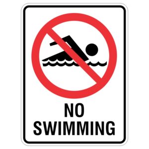 A warning sign featuring a red circle with a diagonal line over a silhouette of a person swimming, accompanied by the text NO SWIMMING in bold letters below.