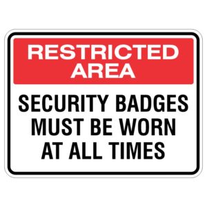 A safety sign indicating a restricted area, with bold red text stating 'RESTRICTED AREA' at the top and 'SECURITY BADGES MUST BE WORN AT ALL TIMES' below in black text.